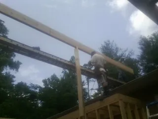 Carpenter setting a ridge beam over a new addition frame — Ice Dam Removal by Roofing Brothers in Duson