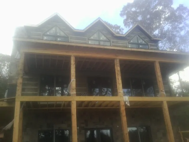 Dormers and porch framing on a large log home under construction — Roof Coating work by our crew in Duson