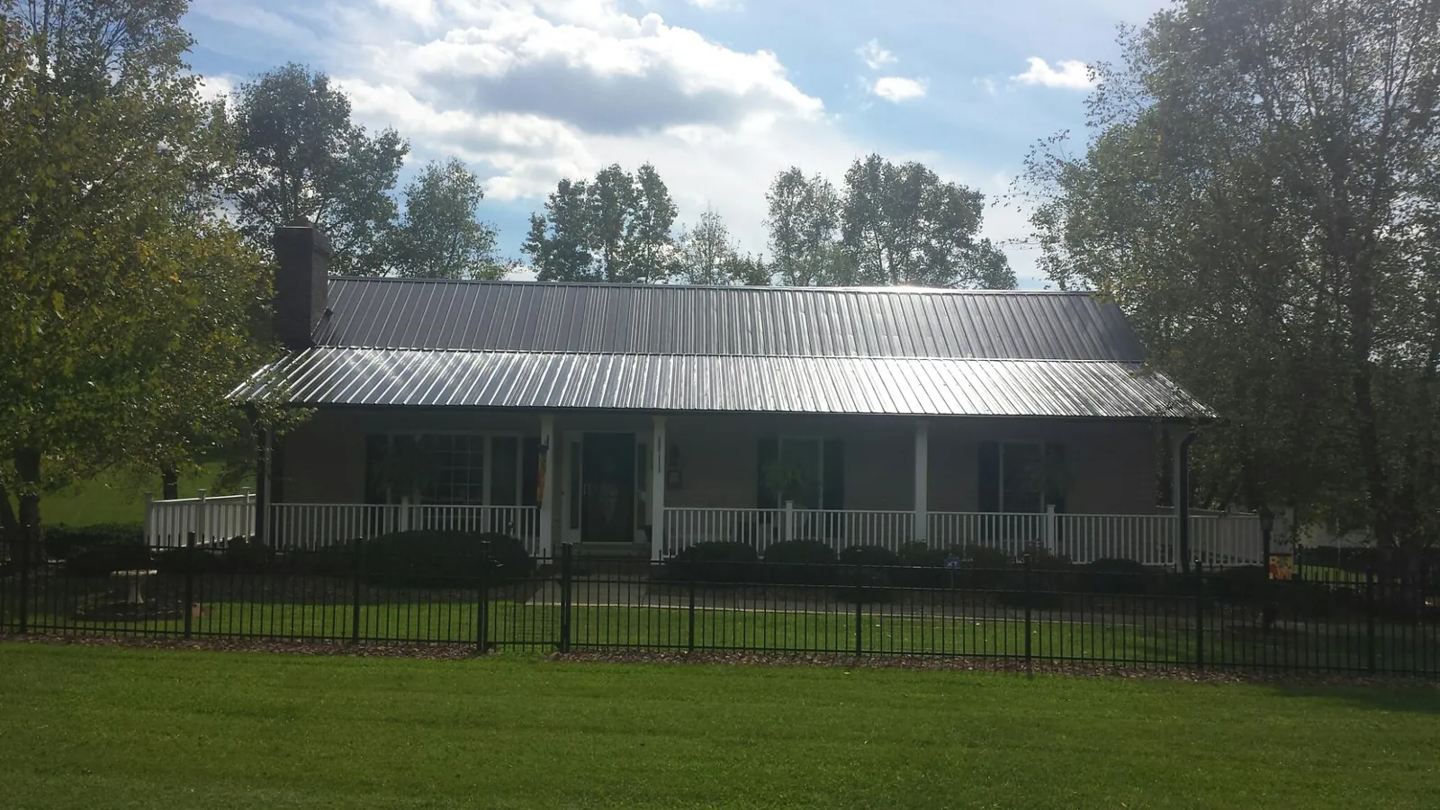 Gray metal roof on a brick ranch with a full width front porch — Gutter Guard Installation work by our crew in Duson