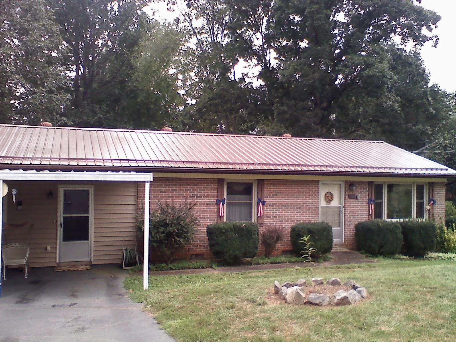 Bronze metal roof and carport on a brick ranch home — Roof Repair work by our crew in Duson